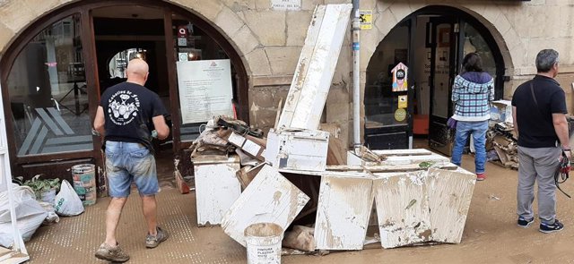 Varias personas trabajan en la limpieza de un comercio afectado por las inundaciones en Tafalla