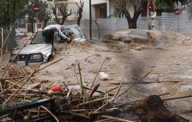 Una pareja saliendo de un coche durante fuertes lluvias en Grecia