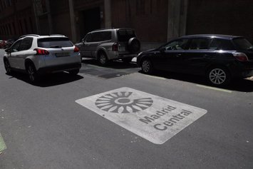Un vehículo junto a una señal de Madrid Central en la acera, que marca la entrada a la zona.