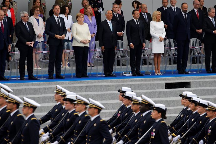 Francia.- Merkel saluda de pie el himno francés durante la conmemoración del Día de la Bastilla