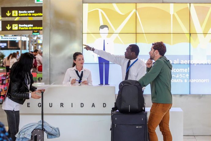 Un trabajador del stand de Seguridad del Aeropuerto Adolfo Suárez Madrid- Barajas, indica a un viajero el acceso al control de seguirdad de la terminal.      