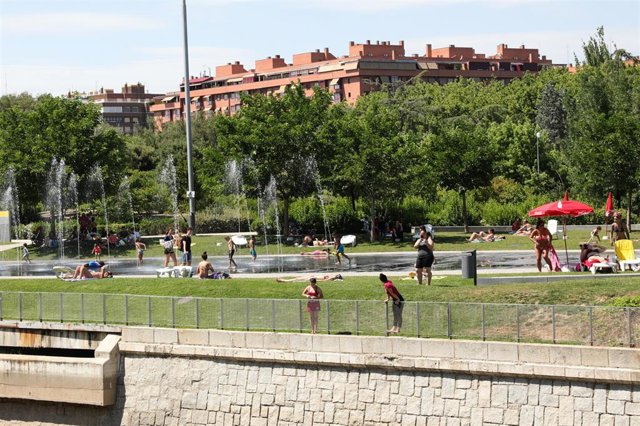 Varias personas, se refrescan de las altas temperaturas en las inmediaciones de los chorros de Madrid Río un día antes de que, según la Agencia Estatal de Meteorología (AEMET), llegue a la península Ibérica y a las Islas Baleares la primera ola de calor d