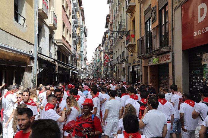 Cientos de personas disfrutan de la música y de los gigantes y cabezudos que animan las calles de Pamplona en plenos San Fermines de 2019.