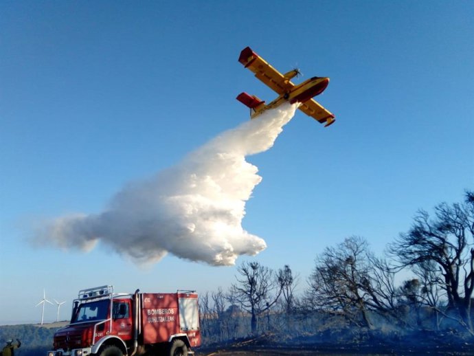 Un avión realiza una descarga de agua sobre los árboles afectados por un incendio
