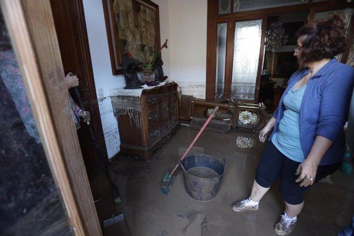 Una mujer achica agua en el interior de su casa en Sant Lloren (Mallorca) tras las inundaciones por las fuertes lluvias 