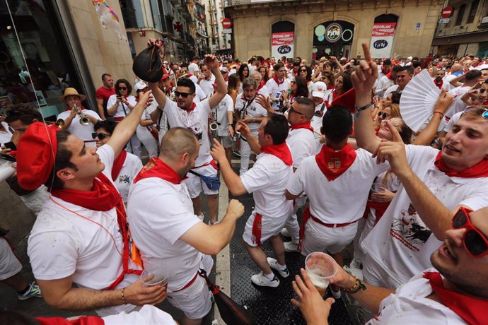 Cientos de personas disfrutan de la música y de los gigantes y cabezudos que animan las calles de Pamplona en plenos San Fermines de 2019.