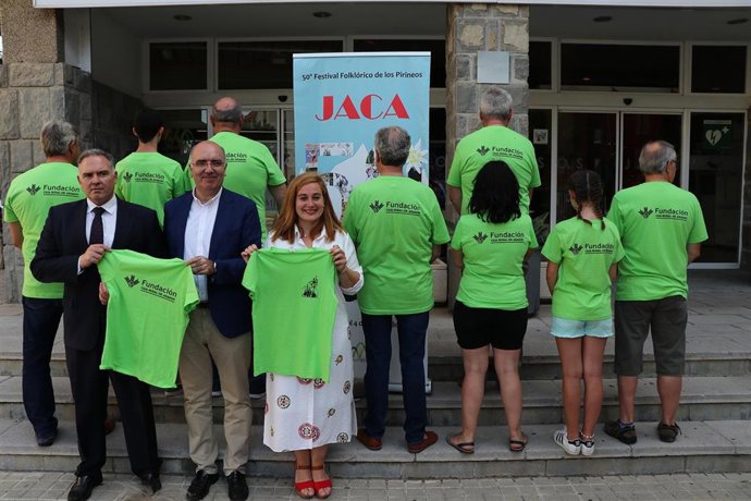 La concejala delegada del Festival Folklórico de los Pirineos, Olvido Moratinos, el director de la Fundación Caja Rural Aragón, José Antonio Artigas, y distintos voluntarios, este lunes 22 en la presentación de estos últimos y su equipación.