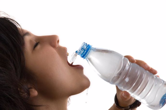 Mujer bebiendo agua de una botella.