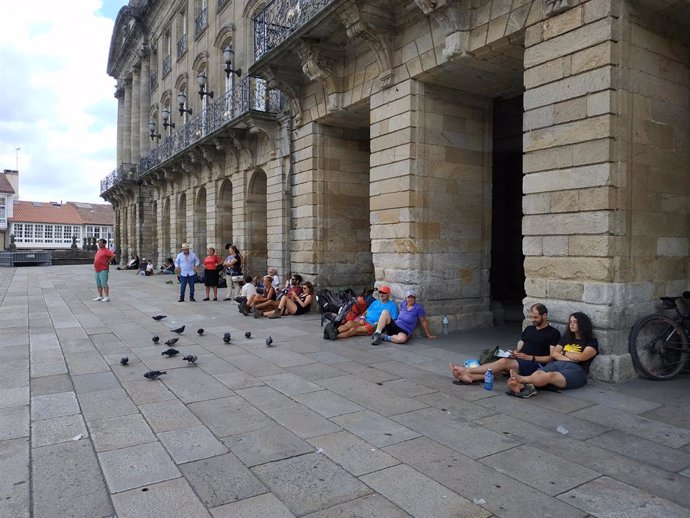 Peregrinos sentados mirando hacia la Catedral de Santiago de Compostela.