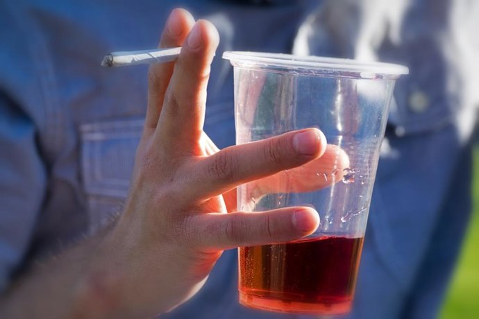 Un joven sujeta un cigarrillo y un vaso con alcohol.