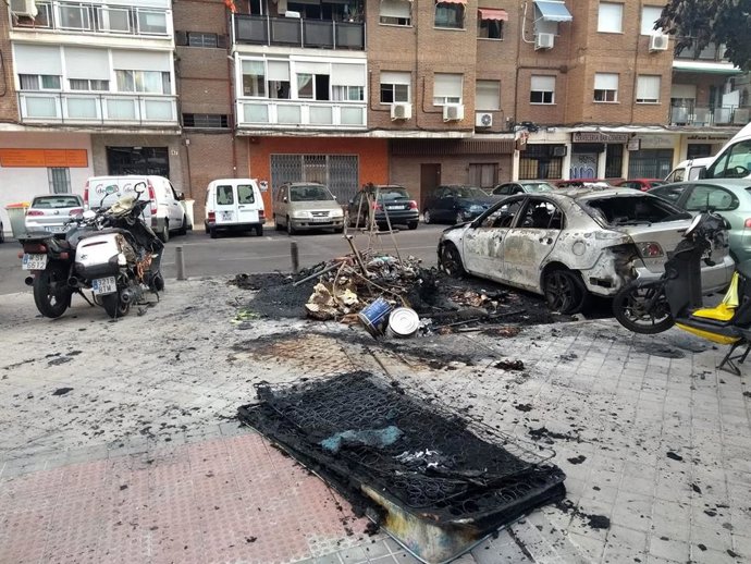Imagen de un contenedor y un vehículo quemados en la calle Verdaguer, en el distrito de Ciudad Lineal.
