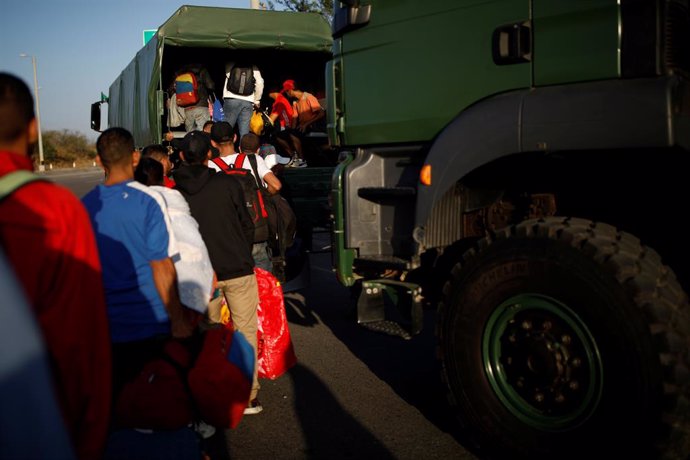 Migrantes venezolanos se suben a un camión para cruzar la frontera de Perú a Ecuador