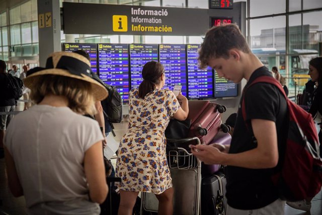 Diferentes viajeros esperanfrente al panel de información de los vuelos de Salida del Aeropuerto 'Josep Tarradellas Barcelona-El Prat', durante la Huelga del personal de tierra de Iberia en Barcelona.