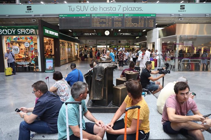 Passatgers en l'estació de tren Puerta d'Atocha de Madrid esperen amb les seves maletes al costat d'un panell d'informació de l'horari de trens durant la primera de les quatre jornades d'aturs parcials de Renfe als quals el sindicat CGT ha convocat als t