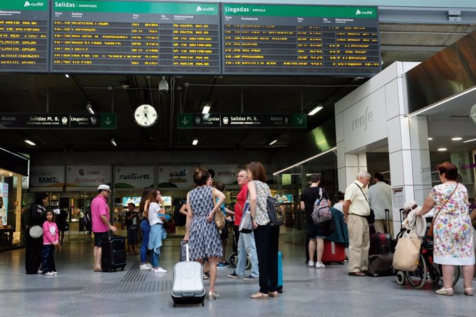 Varios viajeros esperan frente a uno de los paneles de Salidas y Llegadas de la estación de trenes de Atocha durante la primera jornada de paros de Renfe de las cuatro que tienen programadas los sindicatos en verano.