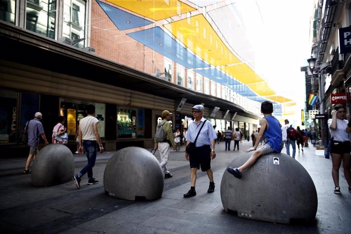 Turistas y vecinos de la zona Centro de Madrid pasean por la calle Preciados bajo la sombra gracias a los toldos instalados.