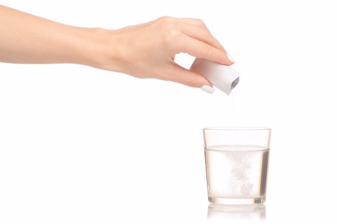 Mano Femenina Sosteniendo Sobre Un Vaso De Agua Un Sobre De Bicarbonato.