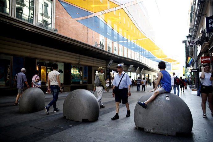 Turistas y vecinos de la zona Centro de Madrid pasean por la calle Preciados bajo la sombra gracias a los toldos instalados.