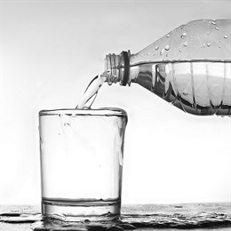 Botella de agua vertiendo a un vaso