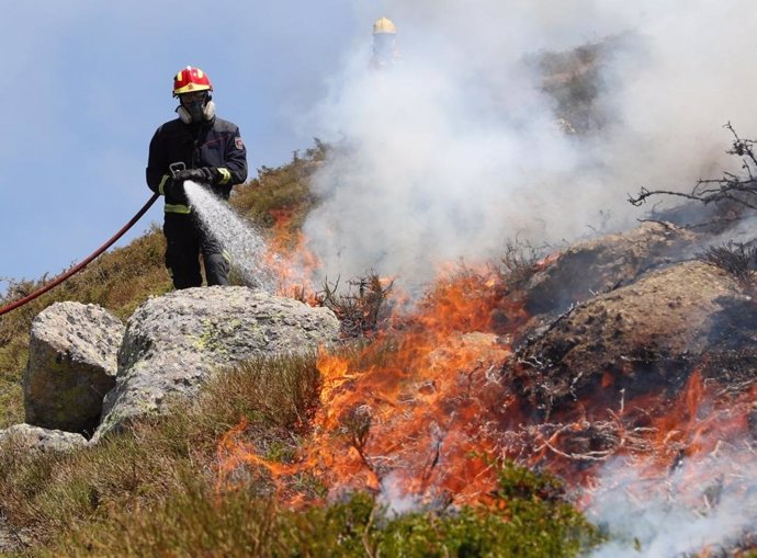 Un bombero de la Comunidad de Madrid trabaja para apagar las llamas registradas en los de Miraflores y La Granja (Segovia).