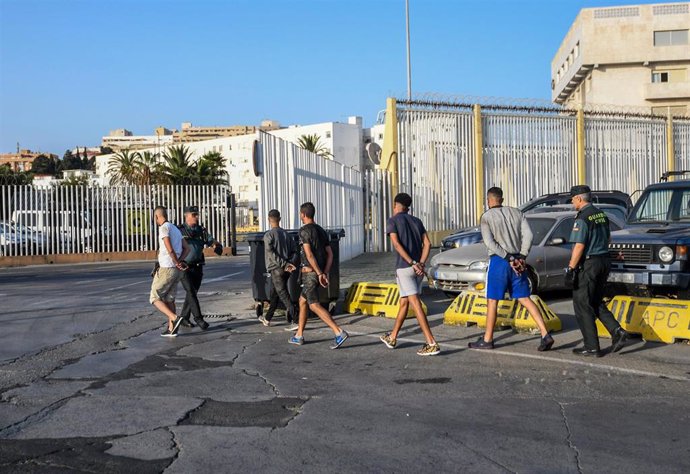 Dos agentes de la Guardia Civil, junto a algunos de los detenidos tras los trabajos de registro de camiones de atracciones en el Puerto de Ceuta en la 'Operación Feriante'.
