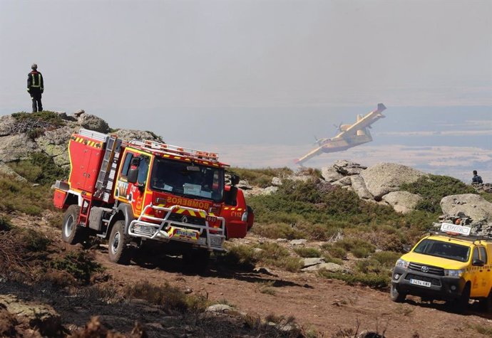 Un camión de bomberos y un vehículo de las brigadas forestales de la Comunidad de Madrid que trabajan en el incendio de Miraflores y de La Granja.