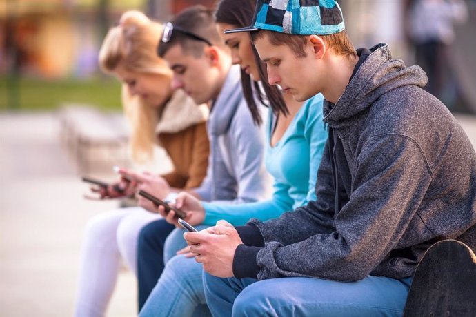 Imagen de archivo de adolescentes utilizando móviles. 