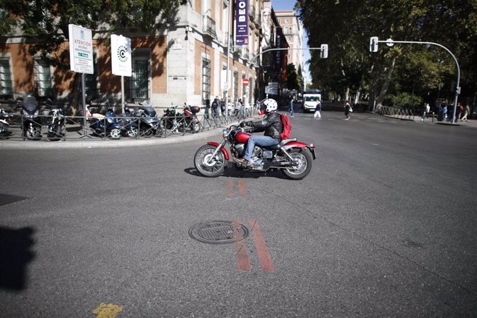 Una motocicleta pasa cerca de una línea naranja que indica restricción al tráfico en el centro de Madrid