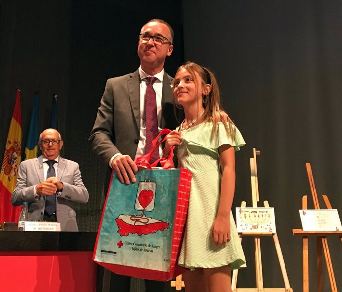 El consejero de Salud, Pablo Fernández Muñiz, entrega el tercer premio del concurso de dibujo del taller La sangre, el líquido de la vida, a Claudia Alba Feito, alumna del CP Alejandro Casona de Cangas del Narcea.