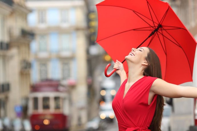 Mujer feliz en la calle con paraguas 