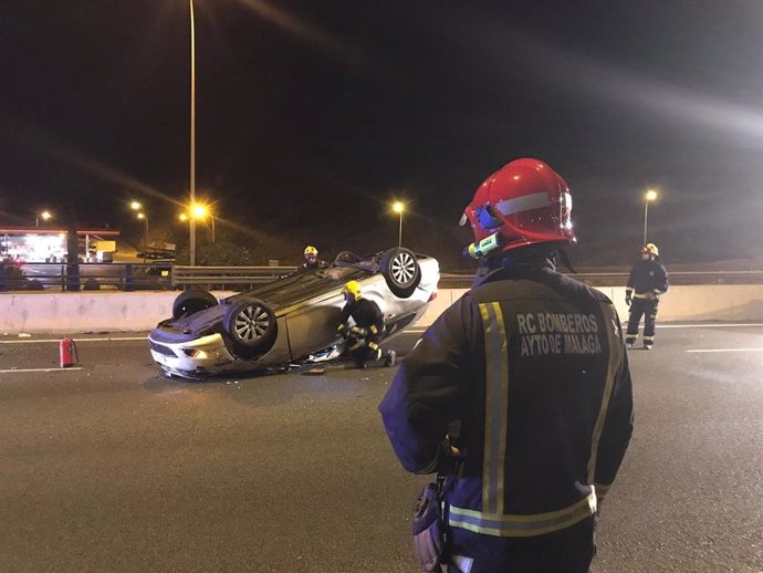 Un efectivo de Bomberos de Málaga mira el coche accidentado en la A-7