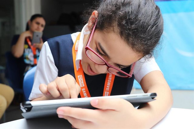 Una niña mira una tablet