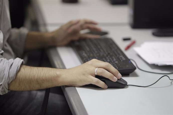 Un trabajador, utilizando el ordenador en la oficina.