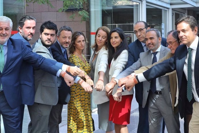 Los diputados de Vox, con su portavoz Rocío Monasterio, muestran pulseras con la bandera de España como muestra de apoyo a un noven afiliado agredido por llevar una.