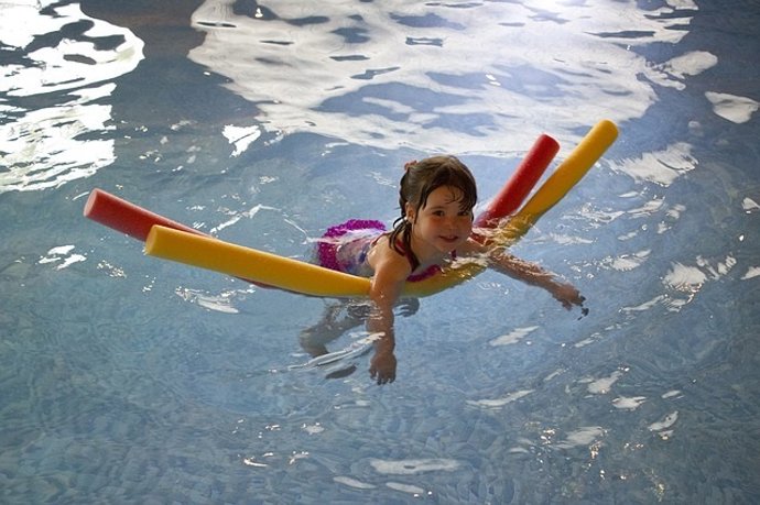 Niña en la piscina bañándose.