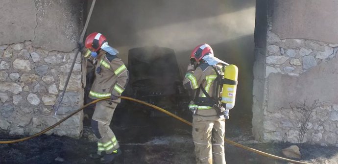 Dos bomberos, durante su actuación en el incendio del vehículo.