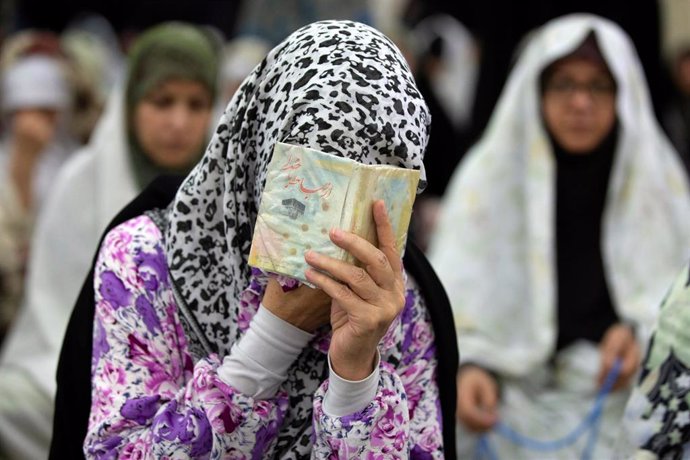 Mujer rejando tamándose con el Corán