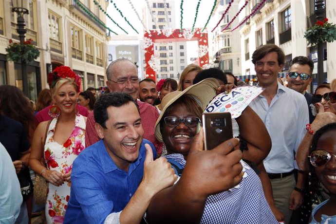 El presidente de la Junta de Andalucía, Juanma Moreno, visita la Feria de Málaga y se fotografía con una turista.