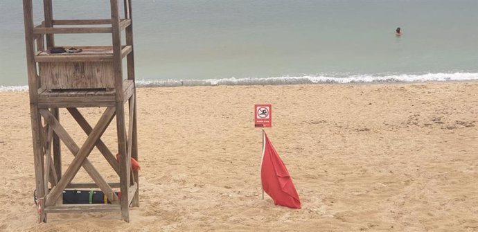 Una playa señalizada con bandera roja por un vertido de aguas mixtas.