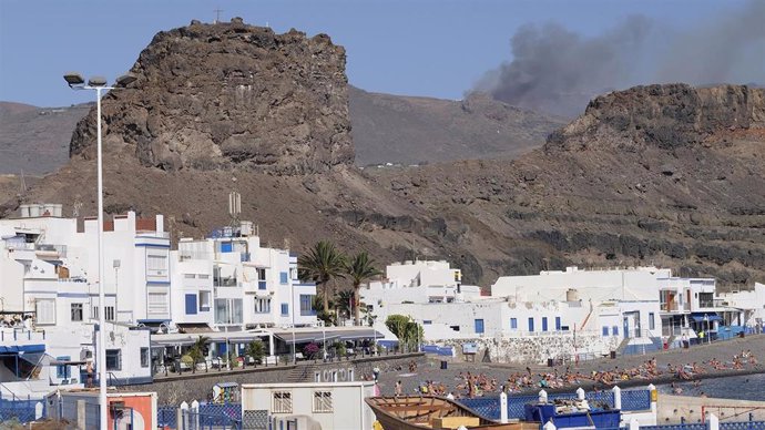 Parte de la zona afectada por el incendio de la isla de Gran Canaria, de la que continúa saliendo humo, junto a un núcleo urbano.