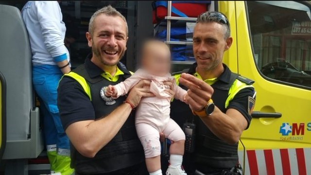 Agentes de Emergencias 112 Comunidad de Madrid posan junto a una bebé de ocho meses que ha sido auxiliada mientras se asfixiaba con un plástico que se había tragado.