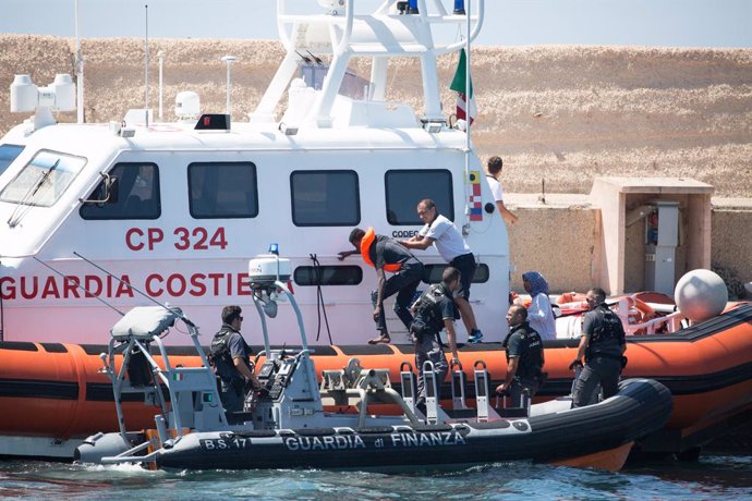 20 August 2019, Italy, Lampedusa: Gurdia vaig donar Finana officials transport a migrant to the port of Lampedusa from the ship "Open Arms" of aid organisation Proactiva Open Arms. Migrants llauri jumping out of desperation from the rescue boat, stran