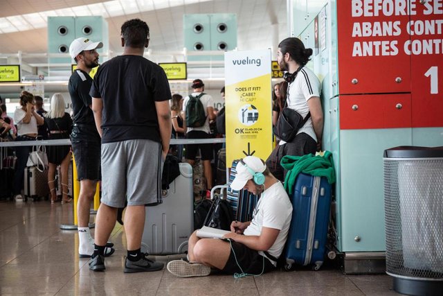 Diferentes viajeros esperan junto al puesto de Check-In de la compañía Vueling en el Aeropuerto 'Josep Tarradellas Barcelona-El Prat', durante la Huelga del personal de tierra de Iberia en Barcelona en julio. 
