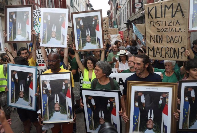 Activists march with stolen portraits of French President Emmanuel Macron during the G7 summit