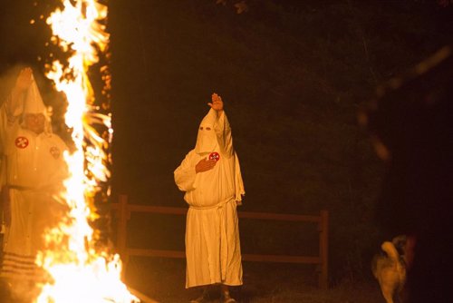 A member of the Ku Klux Klan salutes a lit cross during a cross lighting ceremony at a private residence in Henry County, Virginia, October 11, 2014. The Ku Klux Klan, which had about 6 million members in the 1920s, now has some 2,000 to 3,000 members nat
