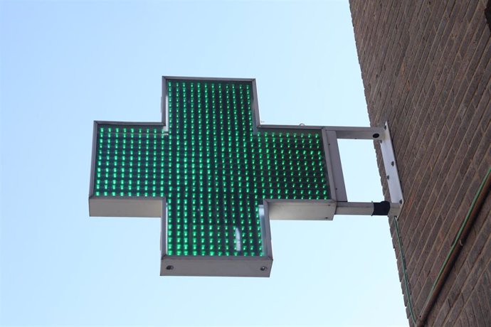 Icono verde encendido de una farmacia en una calle de Madrid.
