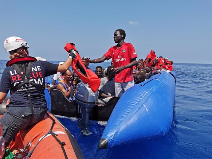 26 August 2019, Libya, --: A rescue crew member gives a life jacket to an African migrant after he and more than hundreds other migrants were rescued by the German aid ship "Eleonore" at the Mediterranean Sea. Photo: Johannes Filous/dpa