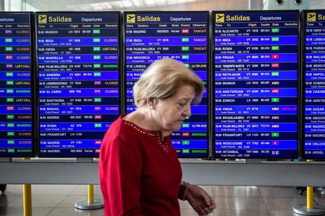 Una mujer pasa frente al panel de infromación de los vuelos de Salida del Aeropuerto 'Josep Tarradellas Barcelona-El Prat', durante la Huelga del personal de tierra de Iberia en Barcelona en julio.