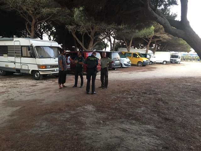 Agentes de la Guardia Civil conversan con un propietario de caravana