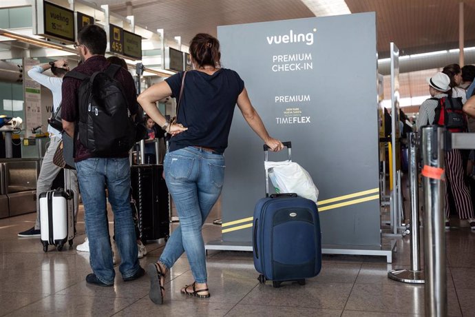 Diferentes viajeros esperan junto al puesto de check-In de la compañía Vueling en el Aeropuerto 'Josep Tarradellas Barcelona-El Prat', durante la huelga del personal de tierra de Iberia en Barcelona en julio.